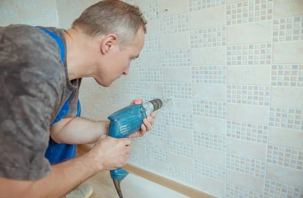 Midden-volwassen man boren gat in de muur — Stockfoto