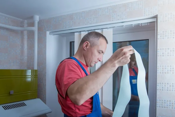 Homem está instalando persianas — Fotografia de Stock