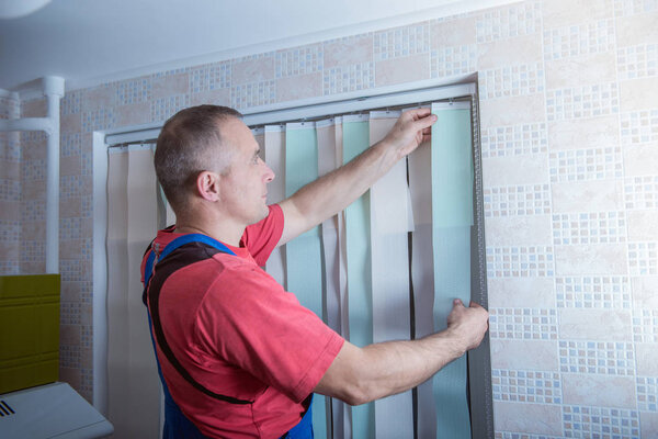 man is installing window blinds,