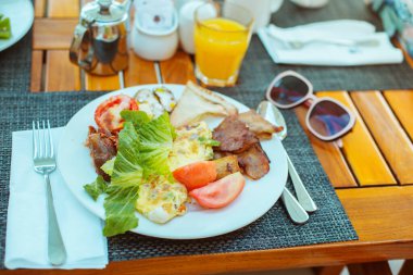  Kahvaltıda. Bir tabak omlet, pastırma ve taze sebze.