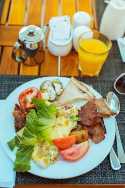 Kahvaltıda. Bir tabak omlet, pastırma ve taze sebze.