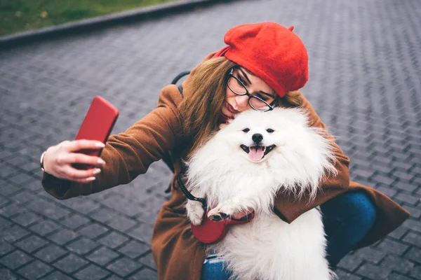Chica hace selfie con un blanco pomeranian . — Foto de Stock