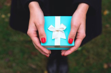 Mavi hediye kutusu Bir kızın ellerinde.