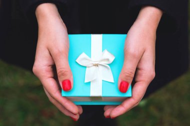 Mavi hediye kutusu Bir kızın ellerinde.