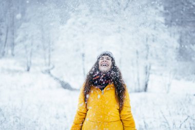 İndirilmiş ceketli kız kış ormanına kar fırlatıyor..