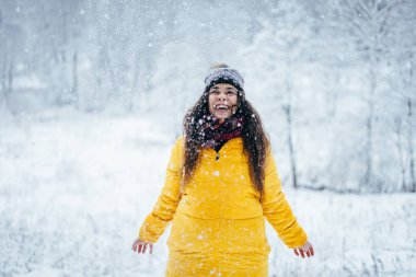 İndirilmiş ceketli kız kış ormanına kar fırlatıyor..