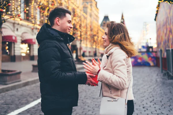 男は女性にクリスマスの背景で路上で贈り物を与えます. — ストック写真