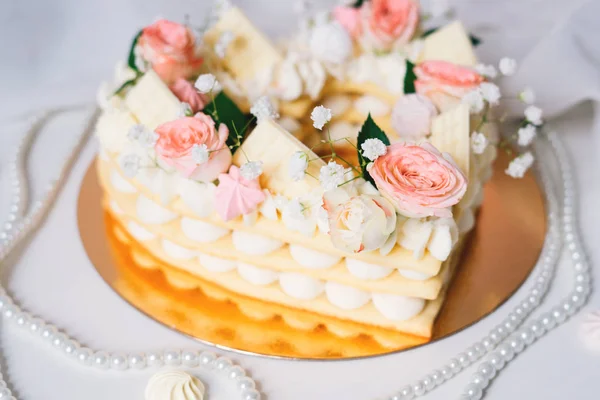 Κέικ σε μορφή καρδιάς με κρέμα και λουλούδια. — Φωτογραφία Αρχείου