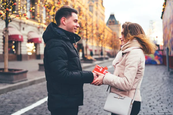 男は女性にクリスマスの背景で路上で贈り物を与えます. — ストック写真