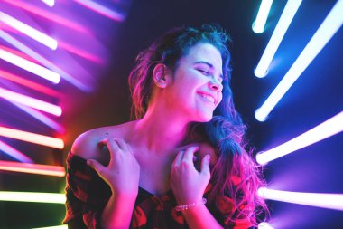 Neşeli, tatlı, gülümseyen kıvırcık kız neon rengi arka planda.
