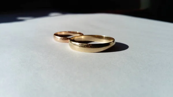 Jóias de ouro, dois anéis de casamento dourados em um fundo branco — Fotografia de Stock