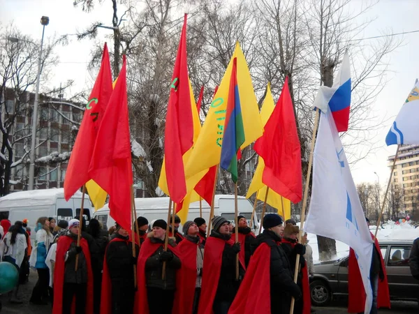 Petrozavodsk, República de Karelia, Rusia - 9 de noviembre de 2019: procesión festiva con banderas brillantes multicolores por las calles de la ciudad. Los hombres llevaban capas rojas y capas. El exterior está nevando y fresco . —  Fotos de Stock