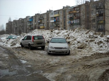 Kar bir arabadan daha uzundur. Birkaç apartman dairesi arasındaki avluda eriyip karlar eriyor. Arabalar çamurlu ve çamurlu su birikintilerinin yanında. Kirli gri kar kamu hizmetleri tarafından temizlenmedi