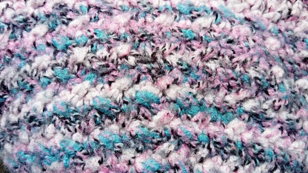 糸の技術を使って合成糸で編む。ニット暖かい冬の製品のクローズアップ-帽子、セーター、ミトン。ピンク、白、黒、緑、青の糸の閉鎖 — ストック写真