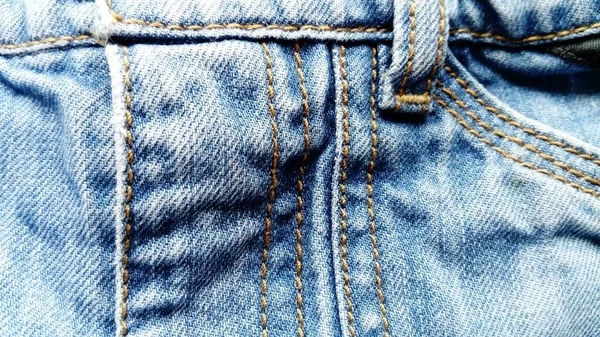 Raues, hartes, dichtes Köpergewebe, aus dem klassische Jeans genäht werden. Jeans in Indigo färbten traditionell nur den Kettfaden. die Nähte sind mit dicken Baumwollfäden von dunkelgelber Farbe genäht — Stockfoto