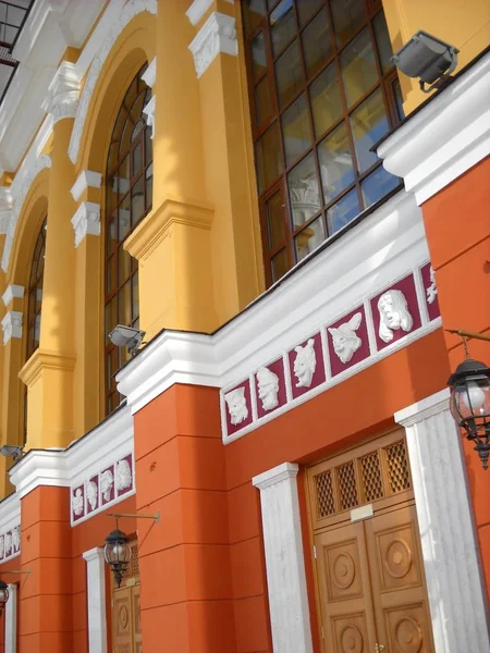 The facade of the building of the Drama Theater. Pilasters are painted white. Walls freshly painted in yellow and orange. Satyr masks,tall glass windows distinguish the exterior of the cultural center — Stock Photo, Image