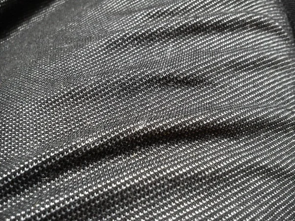 Tissu fabriqué sur un métier à tisser en tissant des fils mutuellement perpendiculaires. Tissu synthétique gris pour la couture de vêtements, d'ameublement et d'autres produits. Gros plan matériel. Ondes froissées sur le tissu — Photo