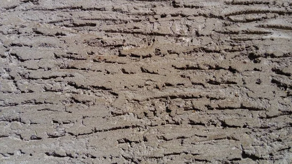 Light and shadow. Wall of the house with a self-made plastered facade. The cement mortar is applied to the wall, smeared with a spatula. A decorative pattern was applied on the plaster with an instant — Stock Photo, Image