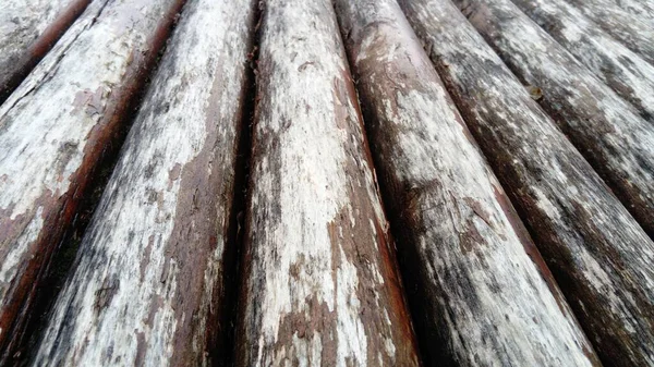 Um tronco de construção para uso em construção sem serragem longitudinal. Variedade de madeira redonda. Fragmento da construção de troncos de madeira arredondados. O efeito da umidade na madeira — Fotografia de Stock