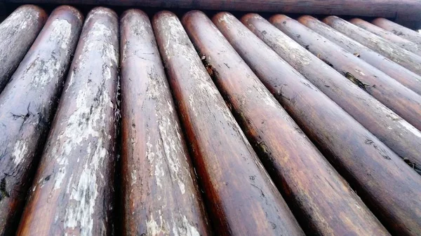 El efecto de la humedad en la madera. Un tronco de construcción para su uso en construcción sin aserrado longitudinal. Surtido de madera redonda. Fragmento de la construcción de troncos redondeados de madera . — Foto de Stock