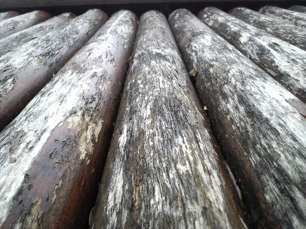El efecto de la humedad en la madera. Un tronco de construcción para su uso en construcción sin aserrado longitudinal. Surtido de madera redonda. Fragmento de la construcción de troncos redondeados de madera . — Foto de Stock