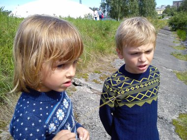 Erkek ve kız kardeş nehrin yanında yürüyorlar. Oğlan ve kız mavi kot pantolon ve mavi örülmüş kalın kazaklar ve yeni yıl süslemeleri giyiyorlar. Yazın başında. Konuşma ve oyun