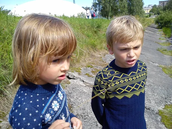 Erkek ve kız kardeş nehrin yanında yürüyorlar. Oğlan ve kız mavi kot pantolon ve mavi örülmüş kalın kazaklar ve yeni yıl süslemeleri giyiyorlar. Yazın başında. Konuşma ve oyun