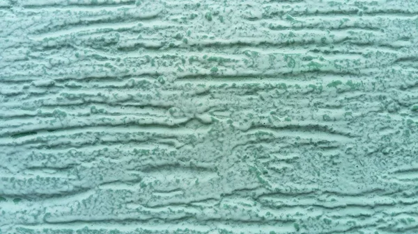 Parede verde rebocada. A camada de acabamento é formada por argamassa endurecida. A textura do cimento é aplicada com uma espátula. O uso de gesso decorativo no interior está se tornando um tipo comum de decoração — Fotografia de Stock