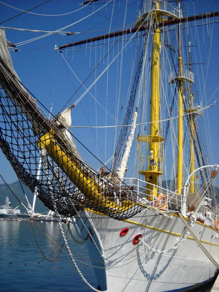 Iate à vela fica no cais. Belo navio, mastro, redes. Homem a bordo . — Fotografia de Stock