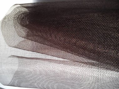 Mosquito net in a roll. Brown synthetic material on a white background. Weaving plastic threads. Convoluted lattice. clipart