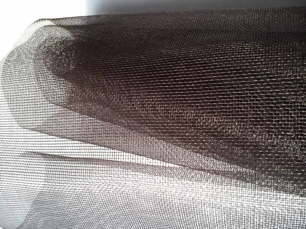 蚊子网在一个滚动。 白色背景上的棕色合成材料。 编织塑料线。 卷曲格子. — 图库照片