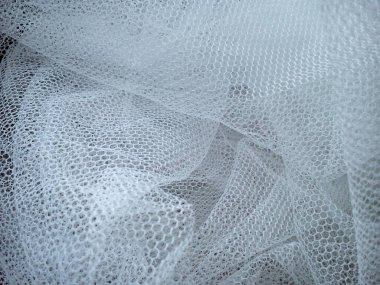 Beyaz buruşuk ağ kumaşı. Sentetik malzemeden yapılmış yıkanabilir bir şey. Sivrisinek ağı yumuşak kıvrımlara katlandı. Duvağa benzeyen kumaş.