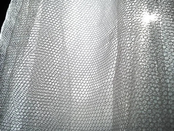 White wrinkled mesh fabric. A washable thing made of synthetic material. Mosquito net folded into soft folds. Fabric similar to a bridal veil