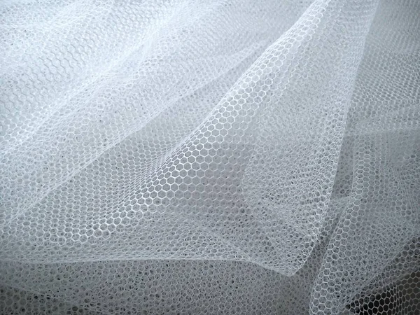 White wrinkled mesh fabric. A washable thing made of synthetic material. Mosquito net folded into soft folds. Fabric similar to a bridal veil