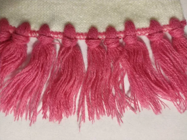 白とピンクの白い糸で作られたスカーフ。白い背景にニットウェア。テキスト用の空のスペース。柔らかいパステルカラー。冬服 — ストック写真