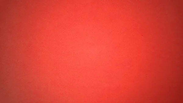 A sheet of bright red paper with light vignetting around the edges. Passionate red color. Saturated bright paint. Paper texture. Background for greeting card or page with the holiday St. Valentine. — 스톡 사진