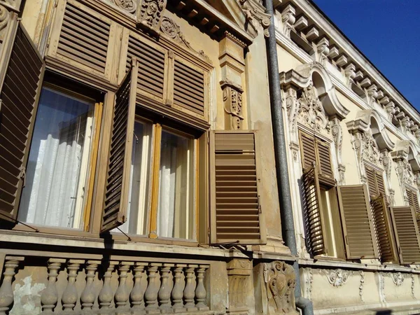 Hermosa fachada de un antiguo edificio en Serbia. Persianas de madera dan a la casa un encanto especial. Las ventanas están cerradas o abiertas con fajas. Marco de ventana tallada, pilastras de pared y columna yeso — Foto de Stock