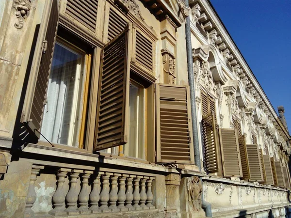 Hermosa fachada de un antiguo edificio en Serbia. Persianas de madera dan a la casa un encanto especial. Las ventanas están cerradas o abiertas con fajas. Marco de ventana tallada, pilastras de pared y columna yeso — Foto de Stock