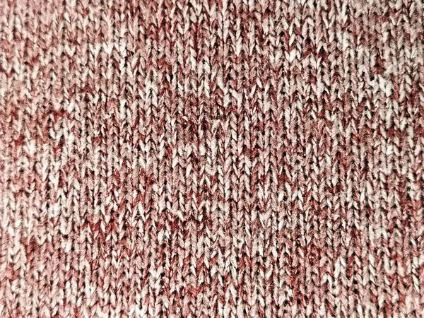 Knitted pattern with the help of knitting needles or crochet. Knitted elastic according to the picture: one front loop, one wrong loop. Knitted warm item. Yarn red and white double color. Close-up