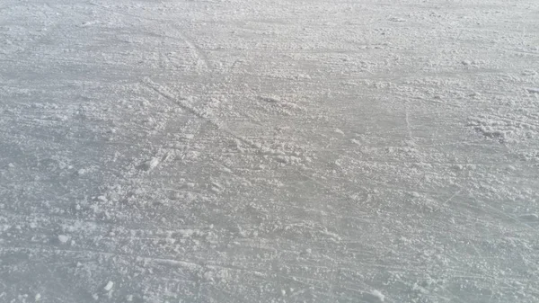 Glace striée avec la pointe des patins à glace. Patinage artistique sur glace. La surface de la patinoire après l'exercice des patineurs. Rayon de soleil sur la glace de printemps humide. Neige et eau gelée — Photo