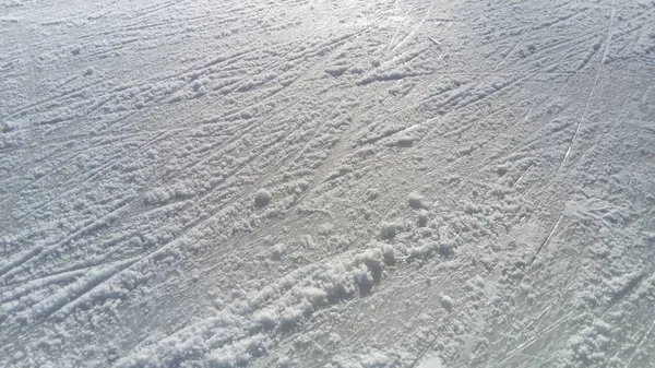 Lód pokryty czubkiem łyżwy figurowej. Jazda figurowa po lodzie. Powierzchnia lodowiska po ćwiczeniach łyżwiarzy. Promień słońca na wilgotnym wiosennym lodzie. Śnieg i woda mrożona — Zdjęcie stockowe