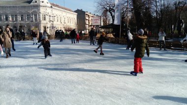 Belgrad, Sırbistan - 10 Ocak 2020 Çocuk ve yetişkinler şehir parkında buz pateni pistine çıktılar. Aktif sporcular eğlenir. Buz pistindeki buz, buz pateninin ucundaki izlerle çizilmiş.