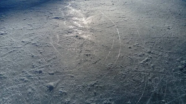 Gelo estriado com a ponta de patins artísticos. Patinação artística no gelo. A superfície da pista de gelo após o exercício de patinadores. Feixe de sol no gelo molhado da mola. Neve e água congelada — Fotografia de Stock