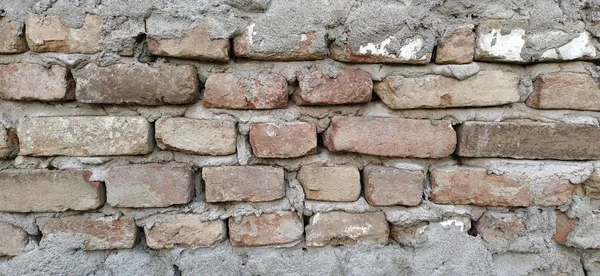 Parede de tijolo. Alvenaria de cerâmica ou cerca. Tijolo velho, irregular, coberto de musgo e mofo em alguns lugares. A textura da pedra ou mineral. O efeito da umidade sobre as estruturas de tijolos. Motivos da aldeia — Fotografia de Stock