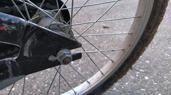 Kerékpár Kerék Acél küllők és központi kerék szerelés a kerékpár keret közelkép. Mogyoró a csavarra. A fémalkatrészeket minőségileg termékké alakítják. Clay és a szennyeződés tapadt a gumi gumiabroncs — Stock Fotó