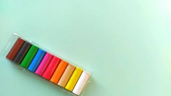 Nuova plastilina multicolore in imballaggi di plastica su fondo verde chiaro. Lastre di plastilina di rosso, rosa, verde, bianco, giallo, marrone, blu, nero. Set per la creatività dei bambini — Foto Stock