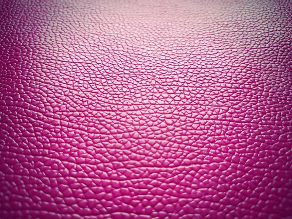 Piel de cerdo artificial en rosa brillante o fucsia. Las ranuras y elevaciones en la superficie de una bolsa o zapato son claramente visibles. Reflejo de la luz. Accesorio de moda. Primer plano. Viñeteo oscuro claro — Foto de Stock