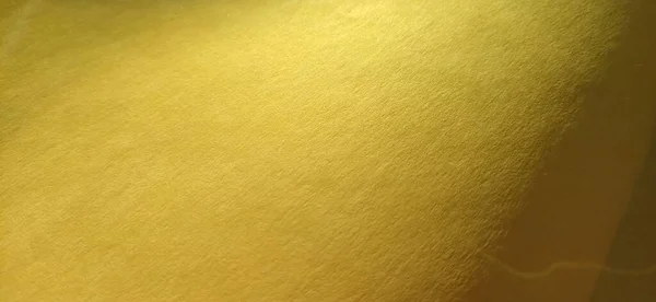 O material de papel ou tecido é amarelo brilhante. Close-up. Folha ligeiramente dobrada. Gradiente de luz e acentuada textura superficial áspera. Amostra de fundo ou produto. Amarelo alegre ensolarado — Fotografia de Stock