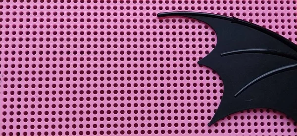 Чёрное крыло летучей мыши из пластика. Розовая панель с отверстиями для мозаики. Детали детских игрушек . — стоковое фото