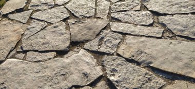 Eski kasabanın merkezindeki büyük düz taşların kaldırımları. Çakıl taşları katmanlara ayrılır ve bir yol taşı gibi sıralanır. Gün batımında taşın doğal gri ve kahverengi tonları